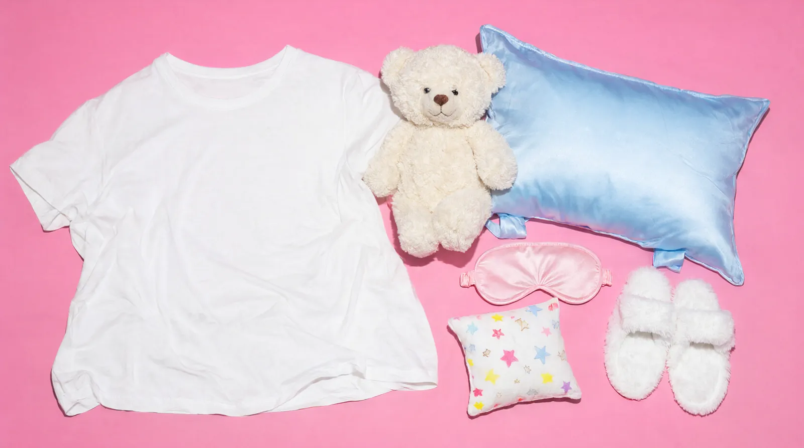 T-shirt pigiama, orsetto, federa e mascherina su fondo rosa